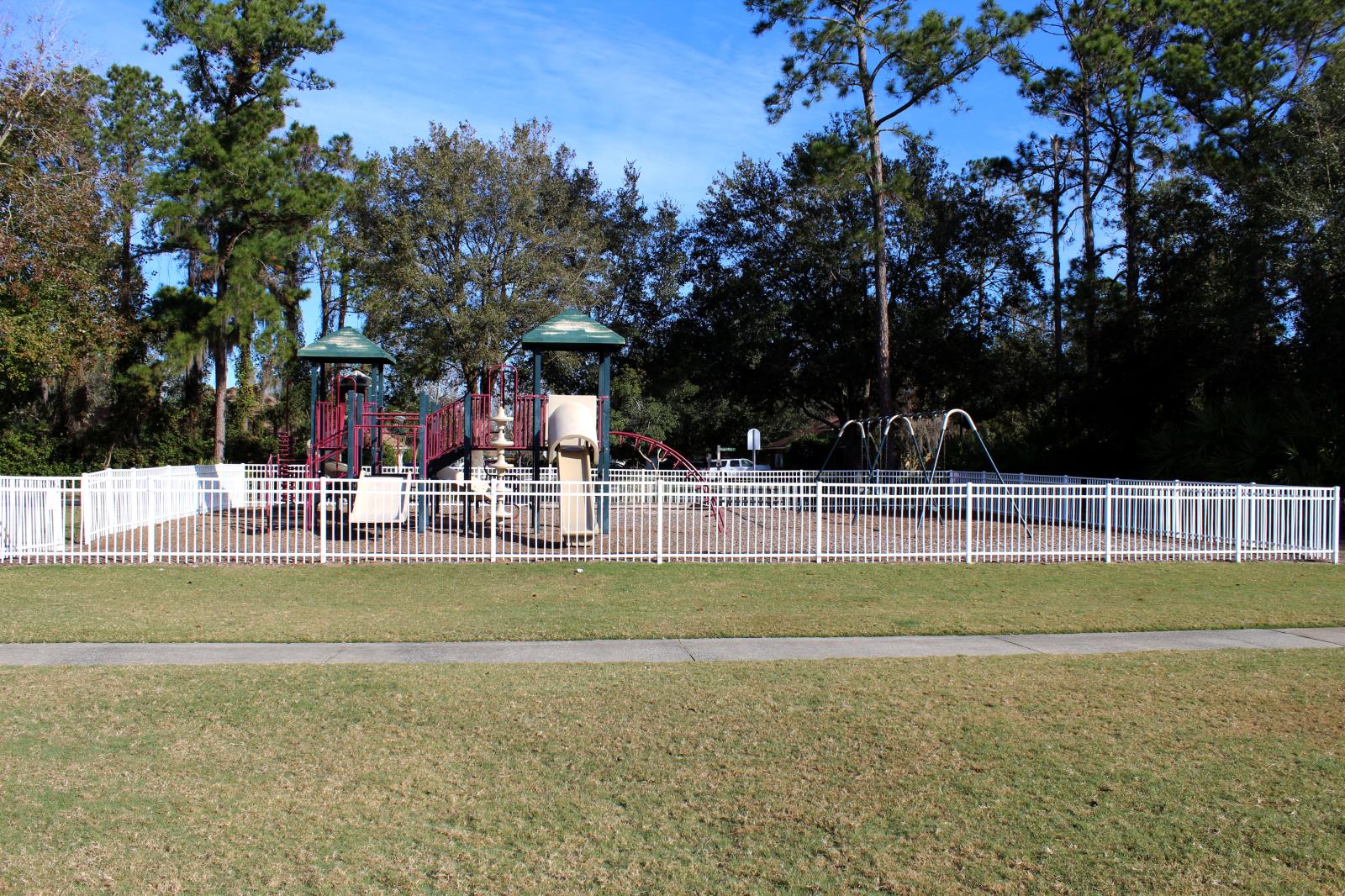 Playground surrounded by a fence with trees in background