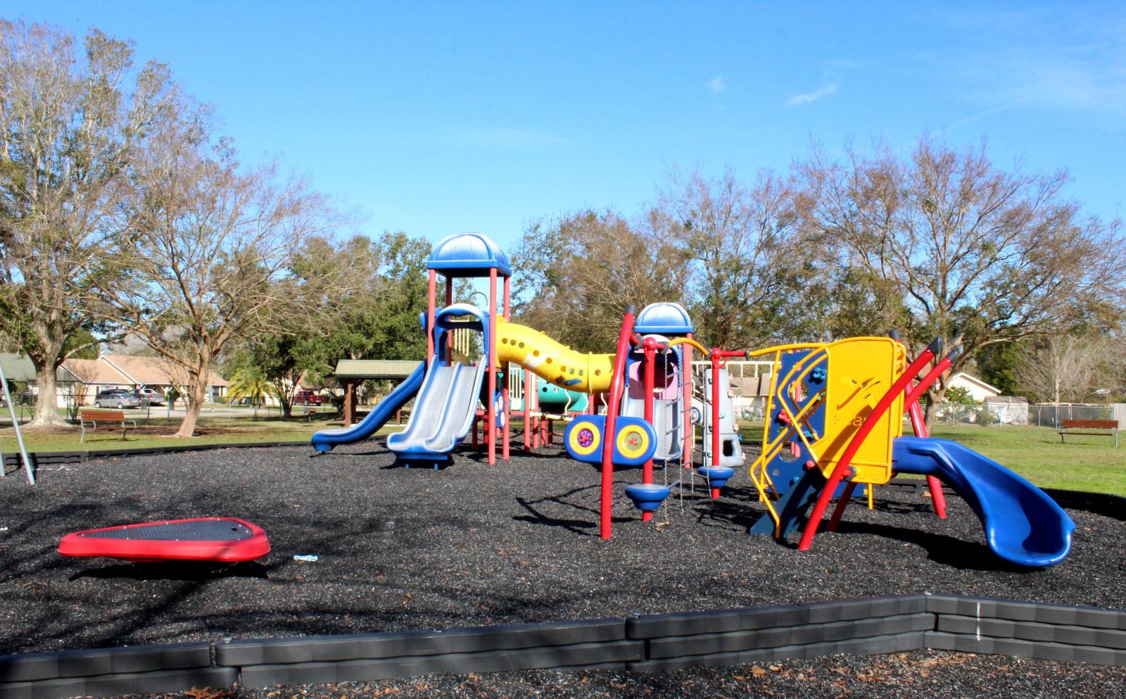 playground with tire shred mulch, benches, trees and houses in background