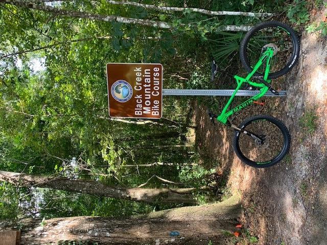 Mountain bike propped against a sign in front of trail