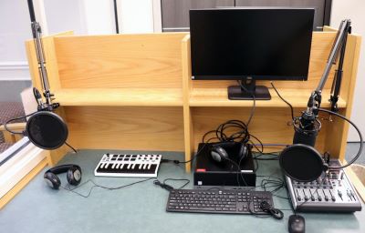 Podcast equipment with microphones, computer, keyboard, on a desk