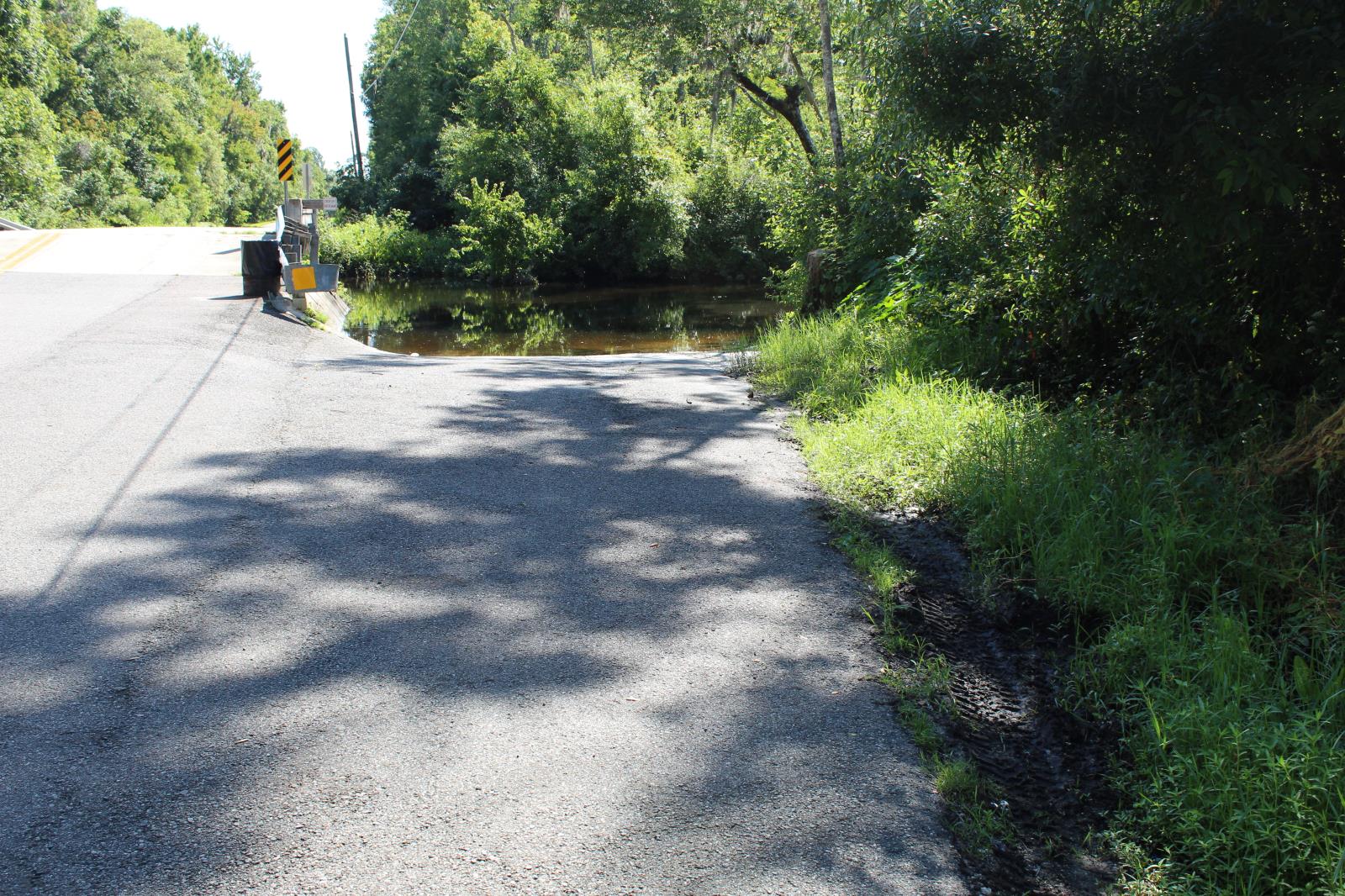 pavement driveway down to water with a guardrail to the left