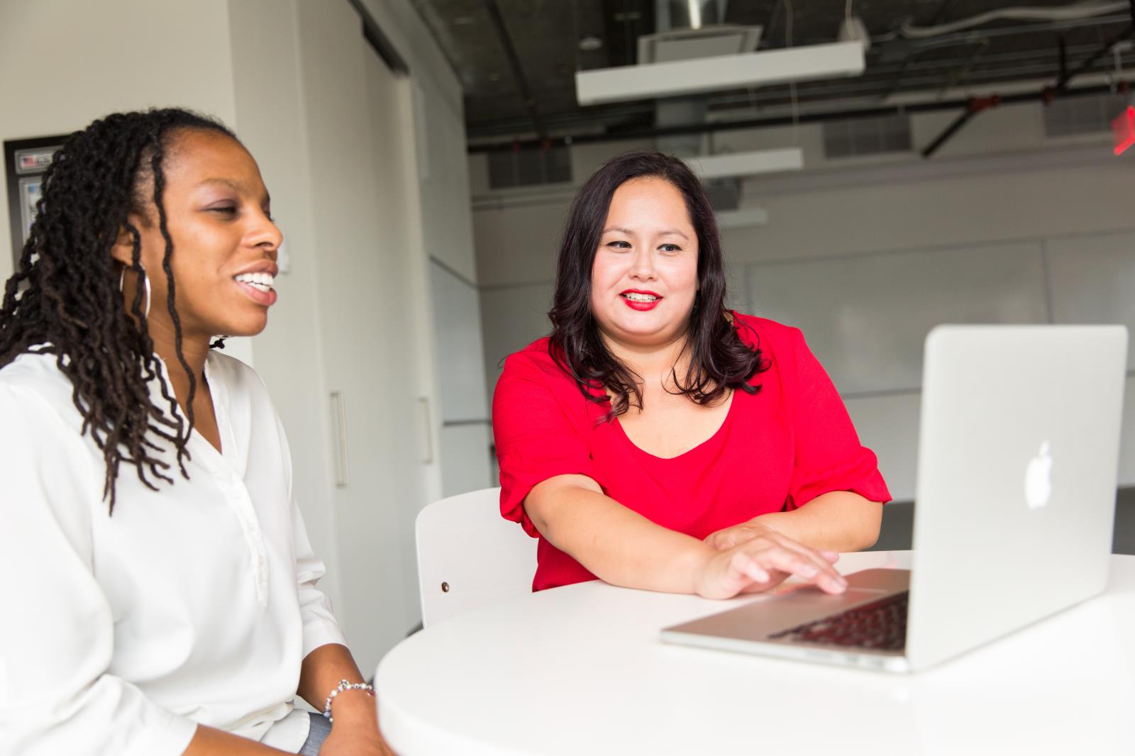 Two ladies sitting next to each other looking at a laptop together