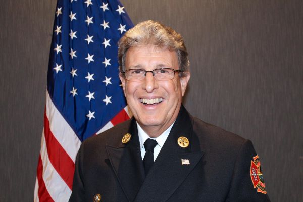 Headshot of Chief Mock posed in front of a flag