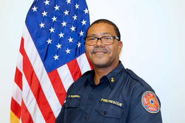 Headshot of Anthony Roseberry posing in front of a flag