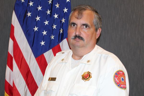 Headshot of Chief Gary O'Conor posing in front of a flag