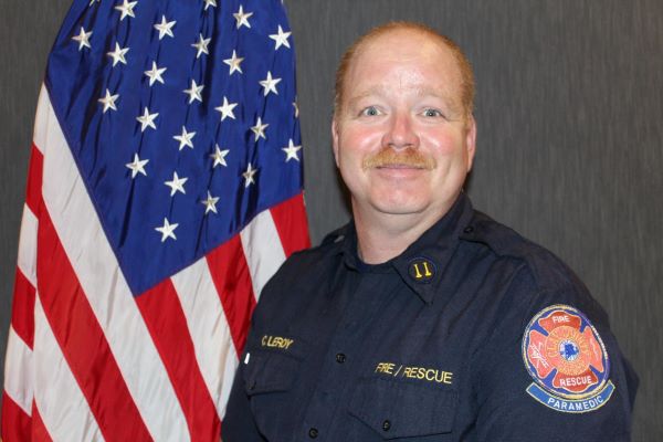 Headshot of Chief Charlie LeRoy posing in front of a flag