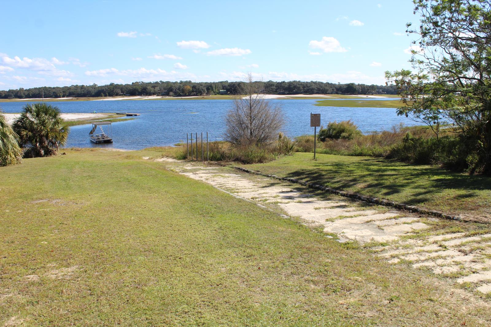 Path in grass leading to lake with trees along the shore