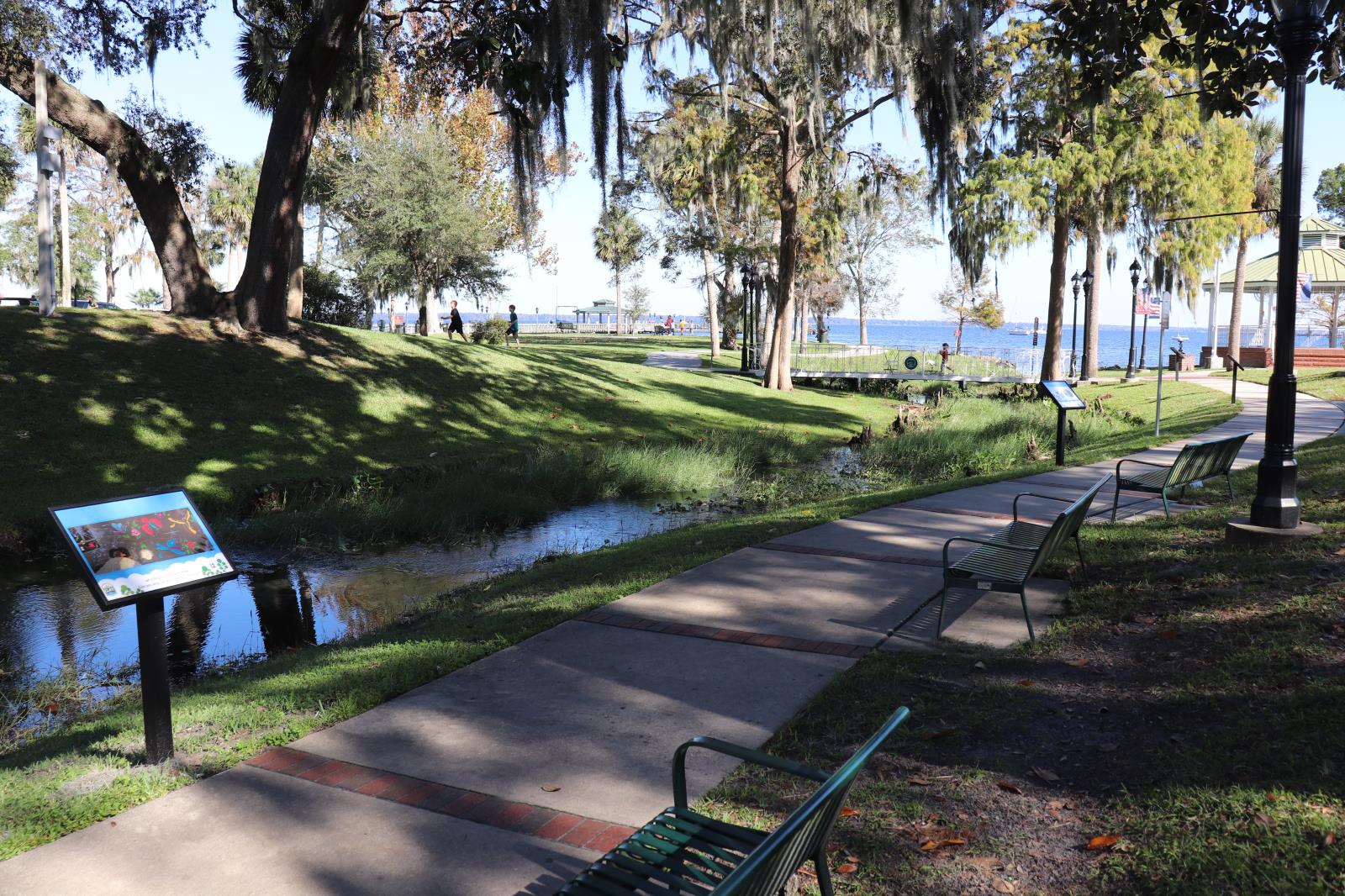 Sidewalk at Spring Park along the inlet with benches and the storywalk frame