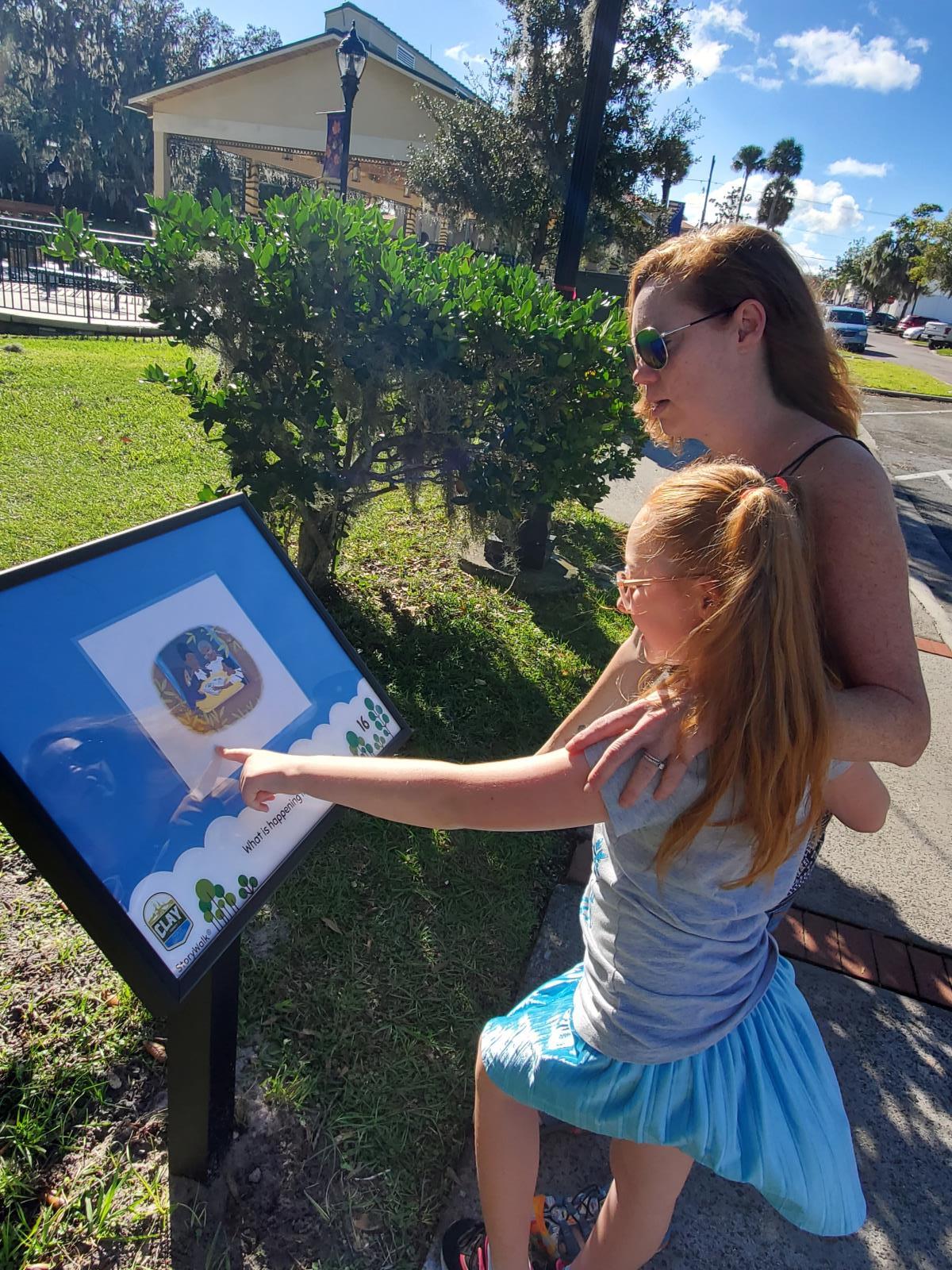 Katie and her daughter Lea looking at a frame with Lea pointing to the page in the frame