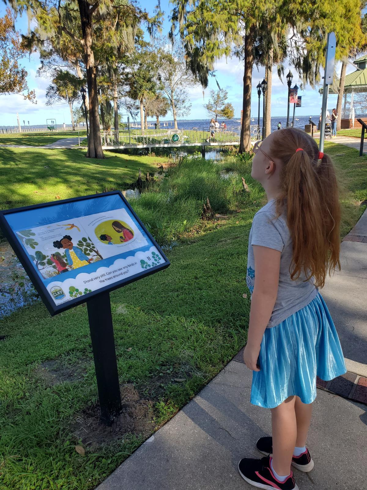 Lea standing in front of a frame with pages from a book looking up towards the trees